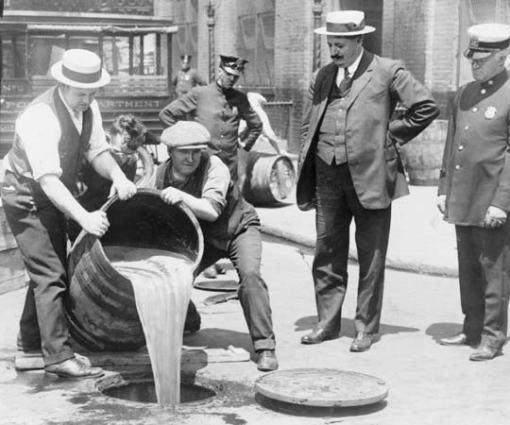 New York City Deputy Police Commissioner John A. Leach (at right in the jaunty straw hat) watches agents pour liquor into a sewer following a raid during the height of prohibition in an undated photo held by the Library of Congress. (REUTERS)